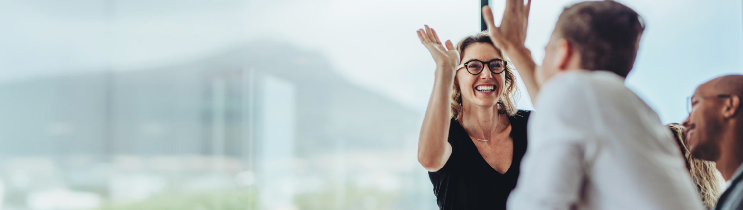 Two colleagues high-fiving in a bright office — celebrating coaching outcomes
