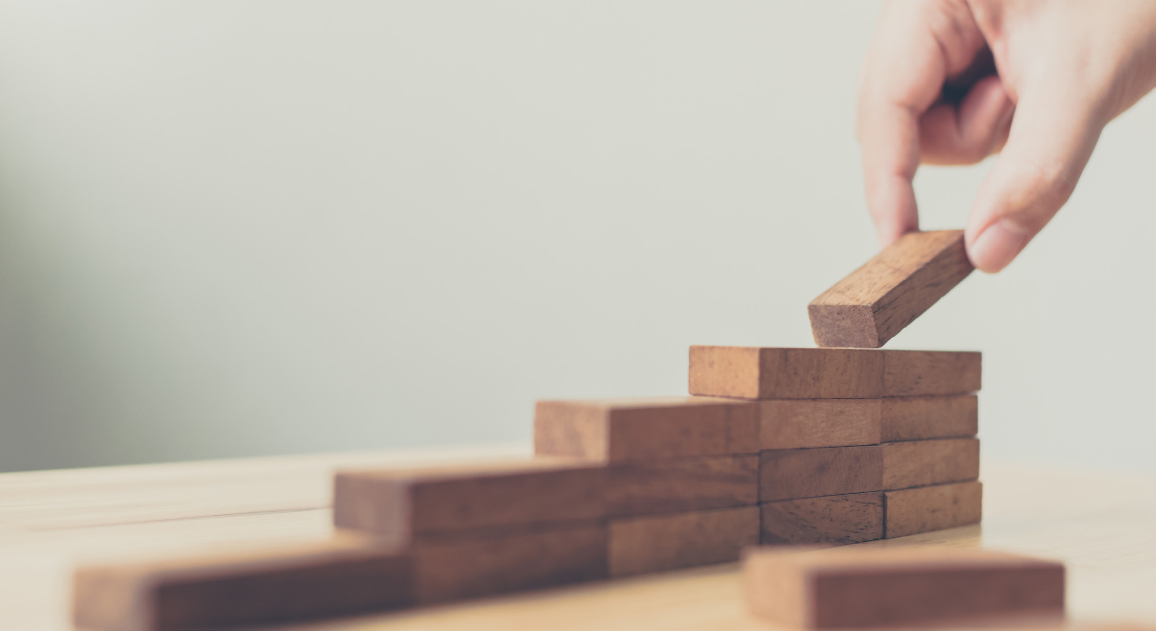 A hand stacking wooden blocks into steps
