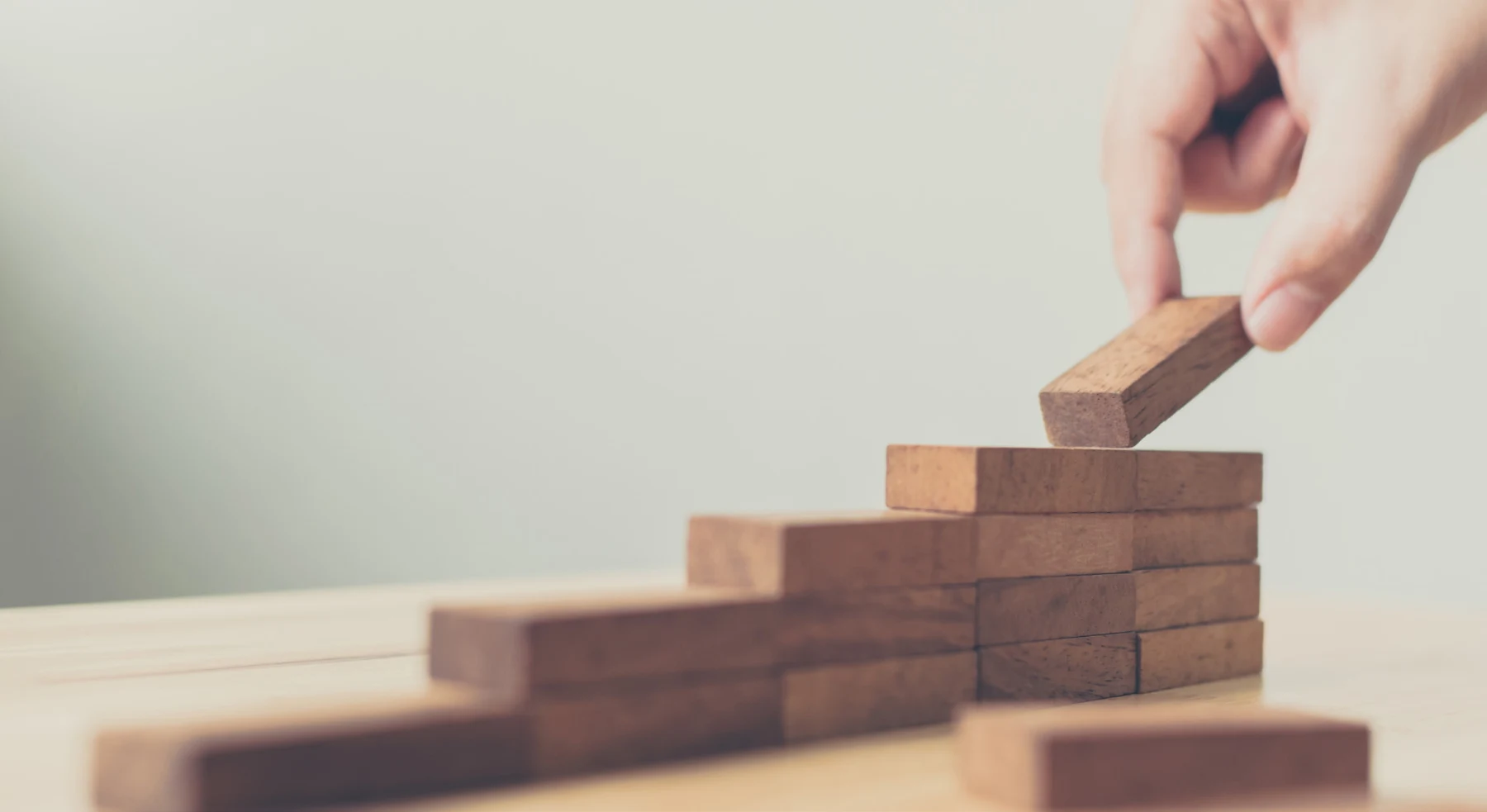 A hand stacking wooden blocks into steps